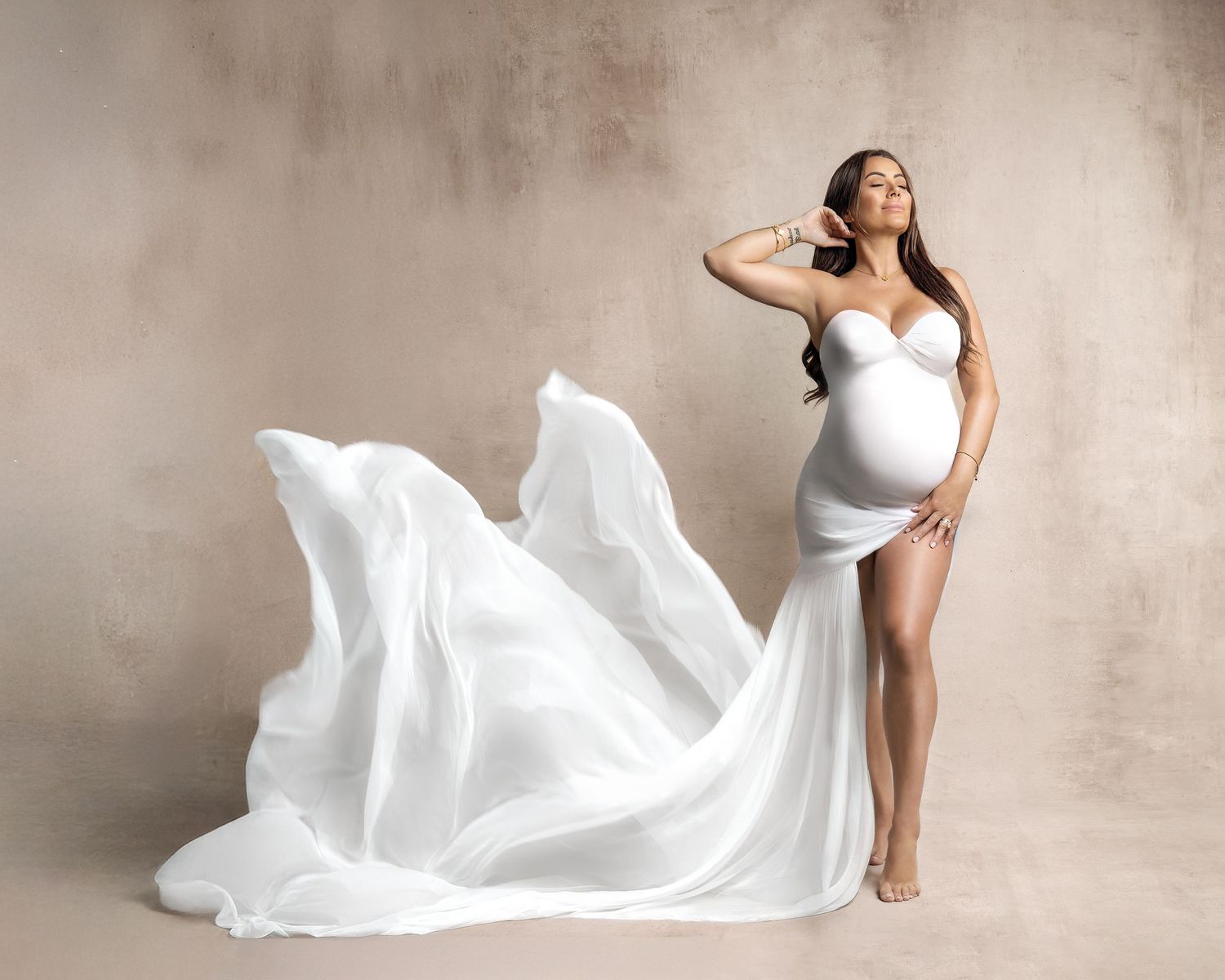 A photo showing a woman wearing a white silk chiffon scry wrapped around her like a gorgeous gown that floats up in an ethereal manner.