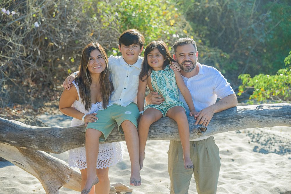 Family enjoying a fun beach photoshoot together on a sunny day at a rocky coastal location.