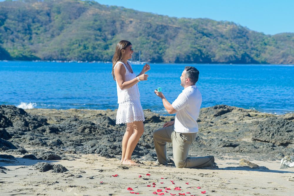 A romantic beach proposal unfolds across multiple photos showing a scenic coastal setting with mountains and blue waters.