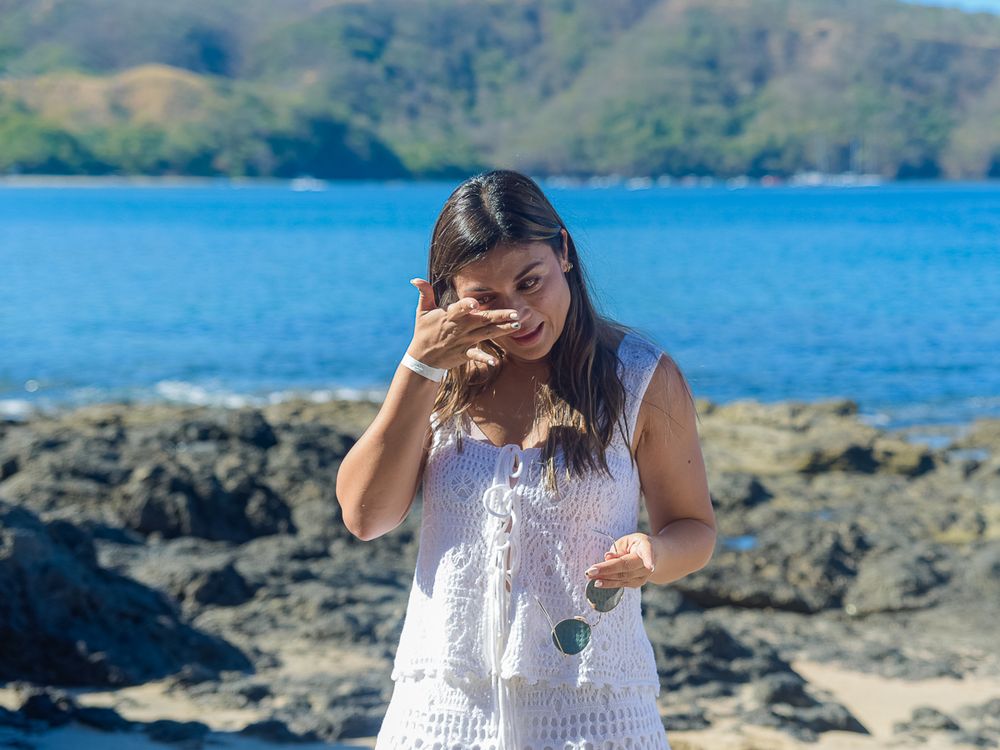 A surprised reaction captured at a scenic coastal location with blue water and rocky shore.