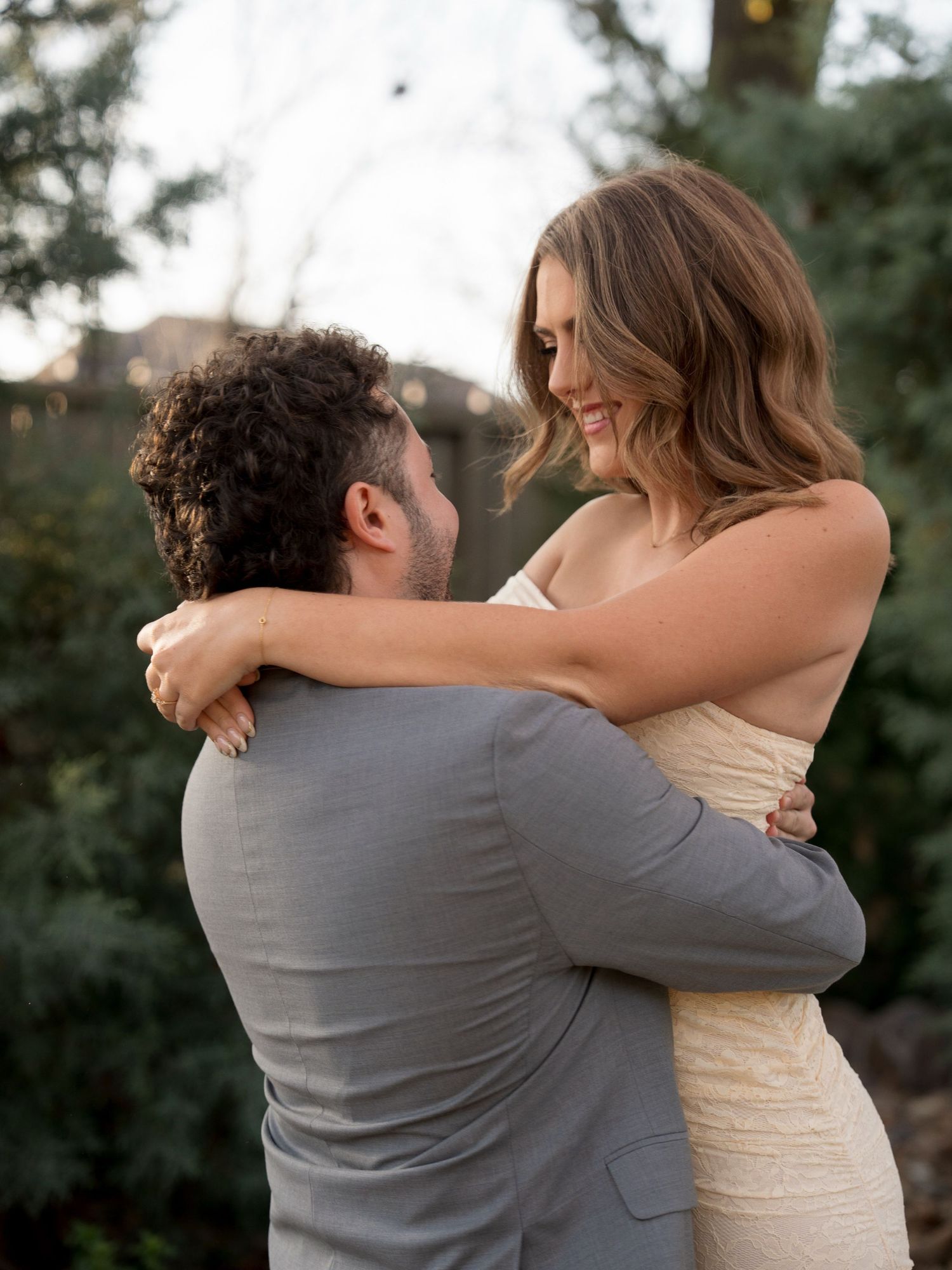 A joyful couple shares a candid laughing moment as the groom carries the bride in her lace wedding dress.