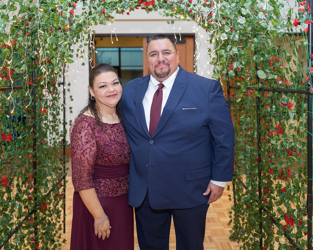 A wedding reception venue decorated with climbing red roses and green vines creating an archway.