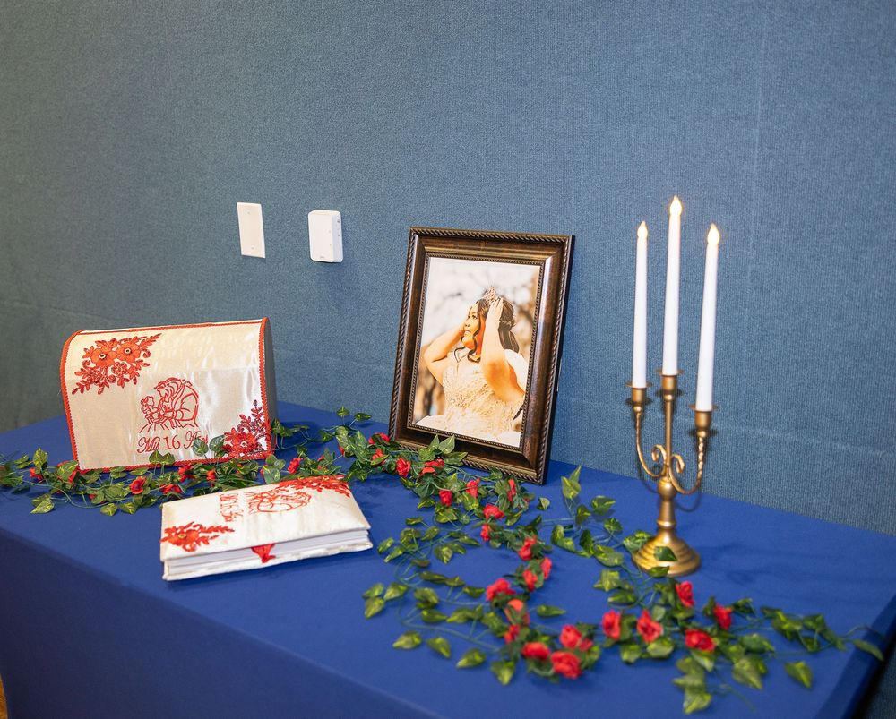 Holiday decorations with red berries, candles, and framed artwork arranged on a blue textured background.
