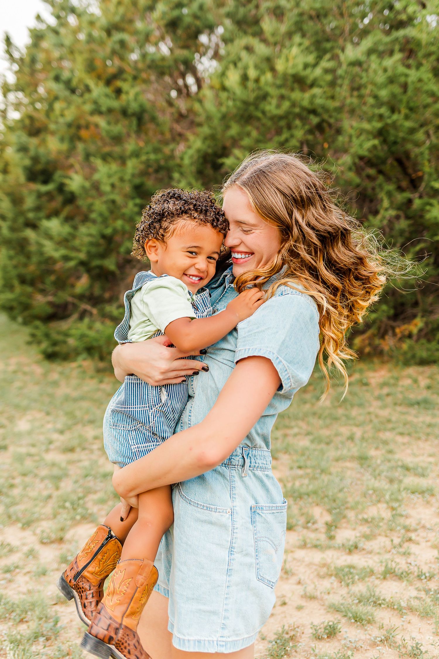 A tender moment shared between parent and child wearing matching denim outfits while embracing outdoors on a sunny day.