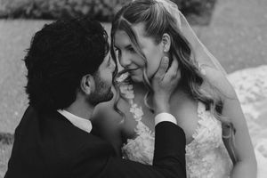 Black and white photo of a groom tenderly holding his bride's face as they share an intimate moment on their wedding day.