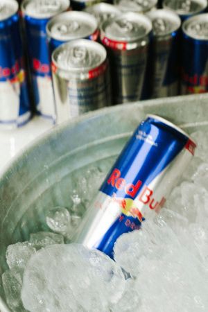 Chilled Red Bull energy drink cans on ice in a metal bucket at an event or party.