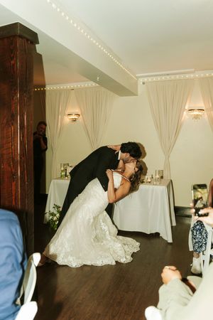 Bride and groom share a romantic dip kiss on the dance floor during their wedding reception.
