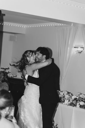 Black and white photo of bride and groom sharing a romantic embrace on the dance floor at their wedding reception.