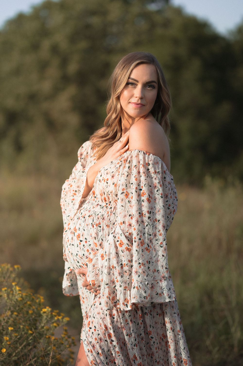 Expectant mother wearing a flowy dress in a green field during a Sioux Falls maternity session.