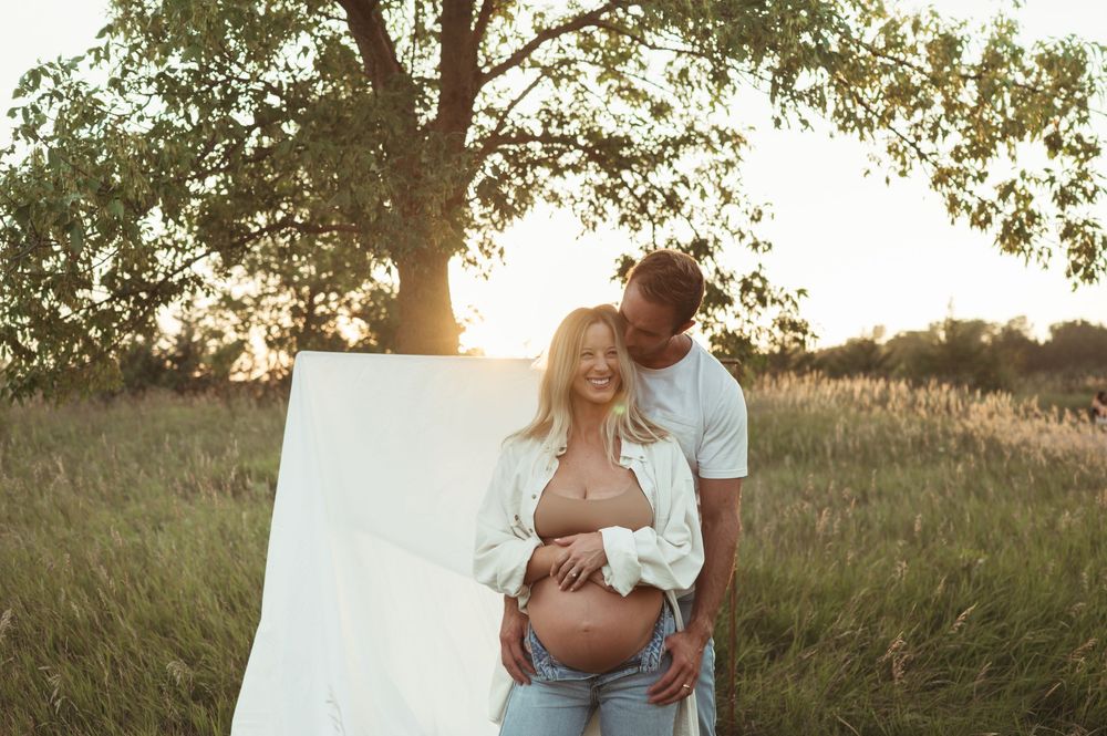 Intimate maternity photography in Sioux Falls with soft green hues and warm golden light.