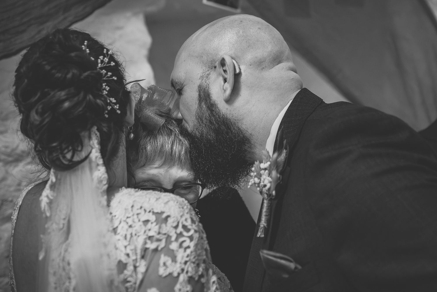 Black and white wedding photo of bride and groom sharing a kiss at the altar.