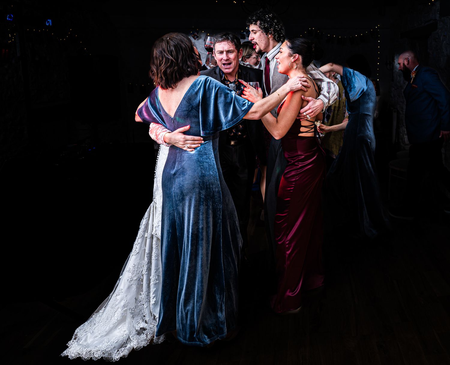 Elegantly dressed guests in formal gowns dance together at an upscale evening event or wedding reception.