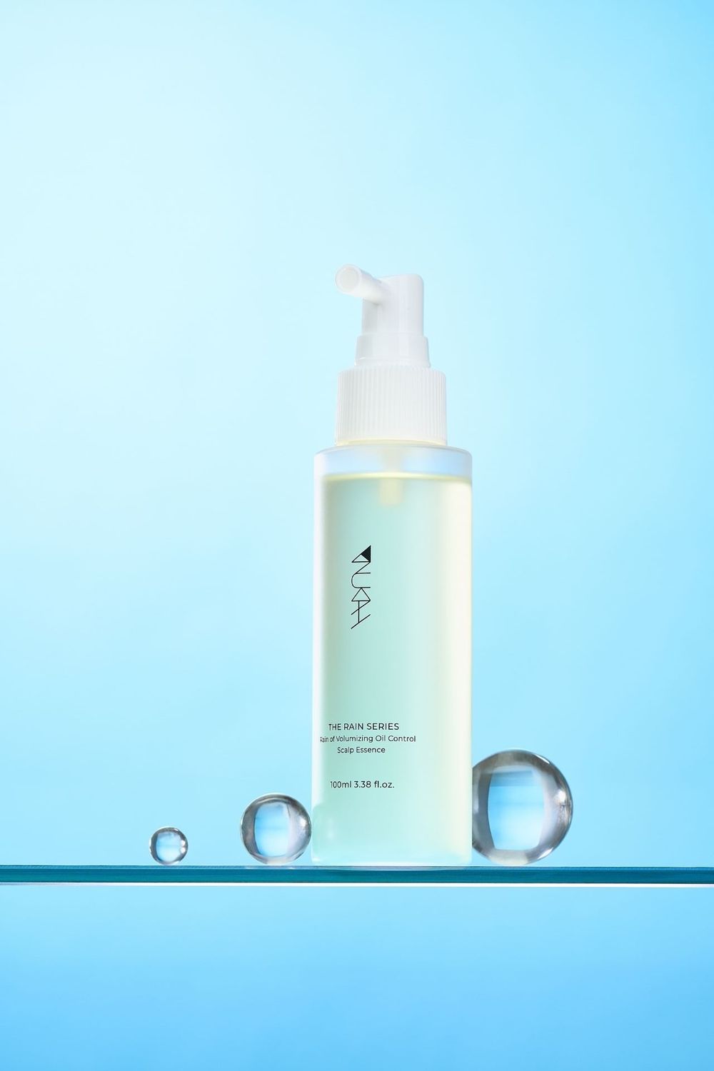 AURA Rain Series moisturizing oil-control daily essence pump bottle with water droplets on blue background.