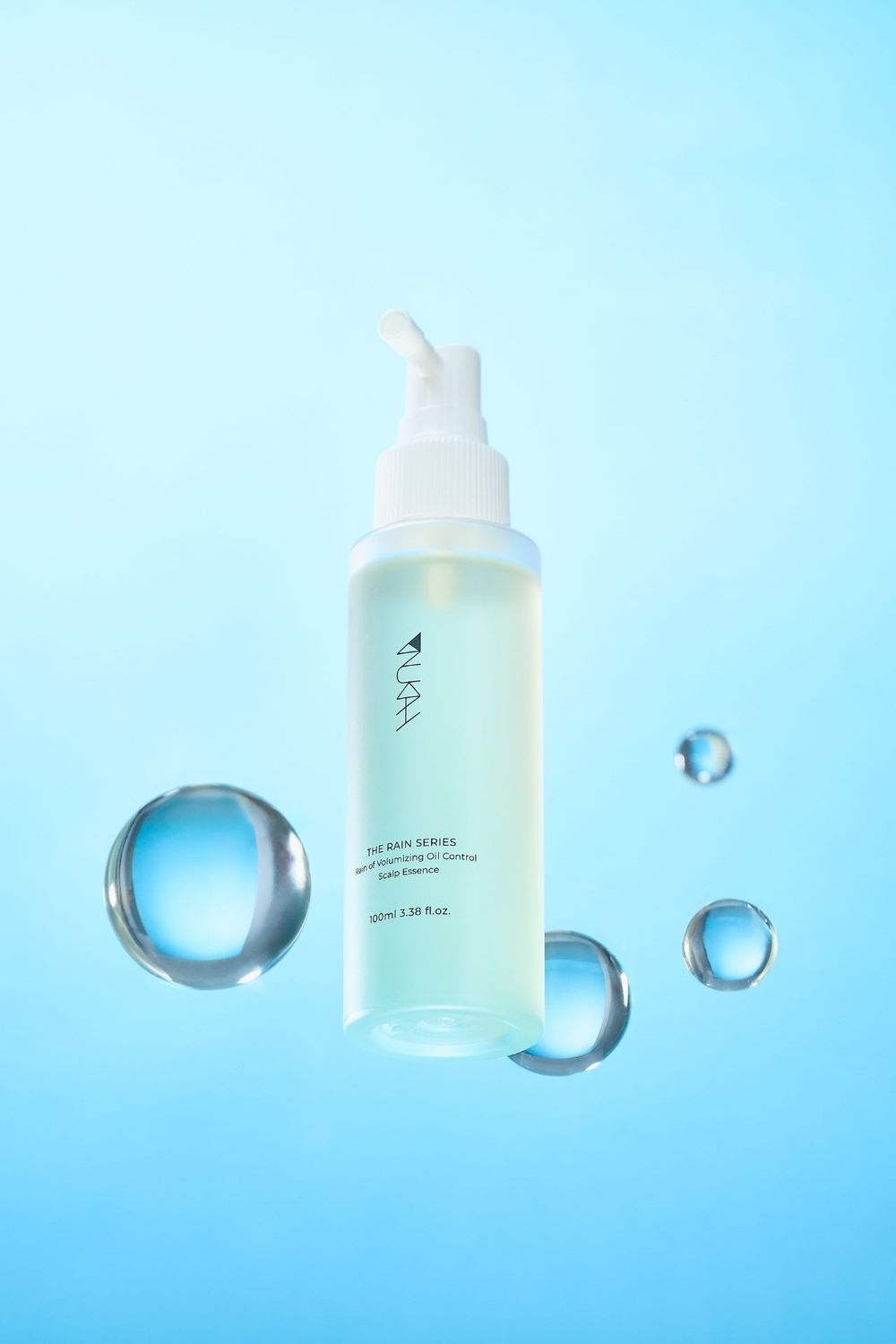 AURA Rain Series moisturizing oil-control daily essence bottle floating with water droplets on light blue background.