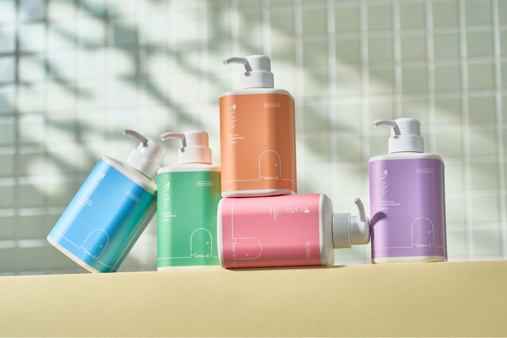 Colorful pastel pump bottles of shampoo and conditioner arranged on a light surface with soft shadows.