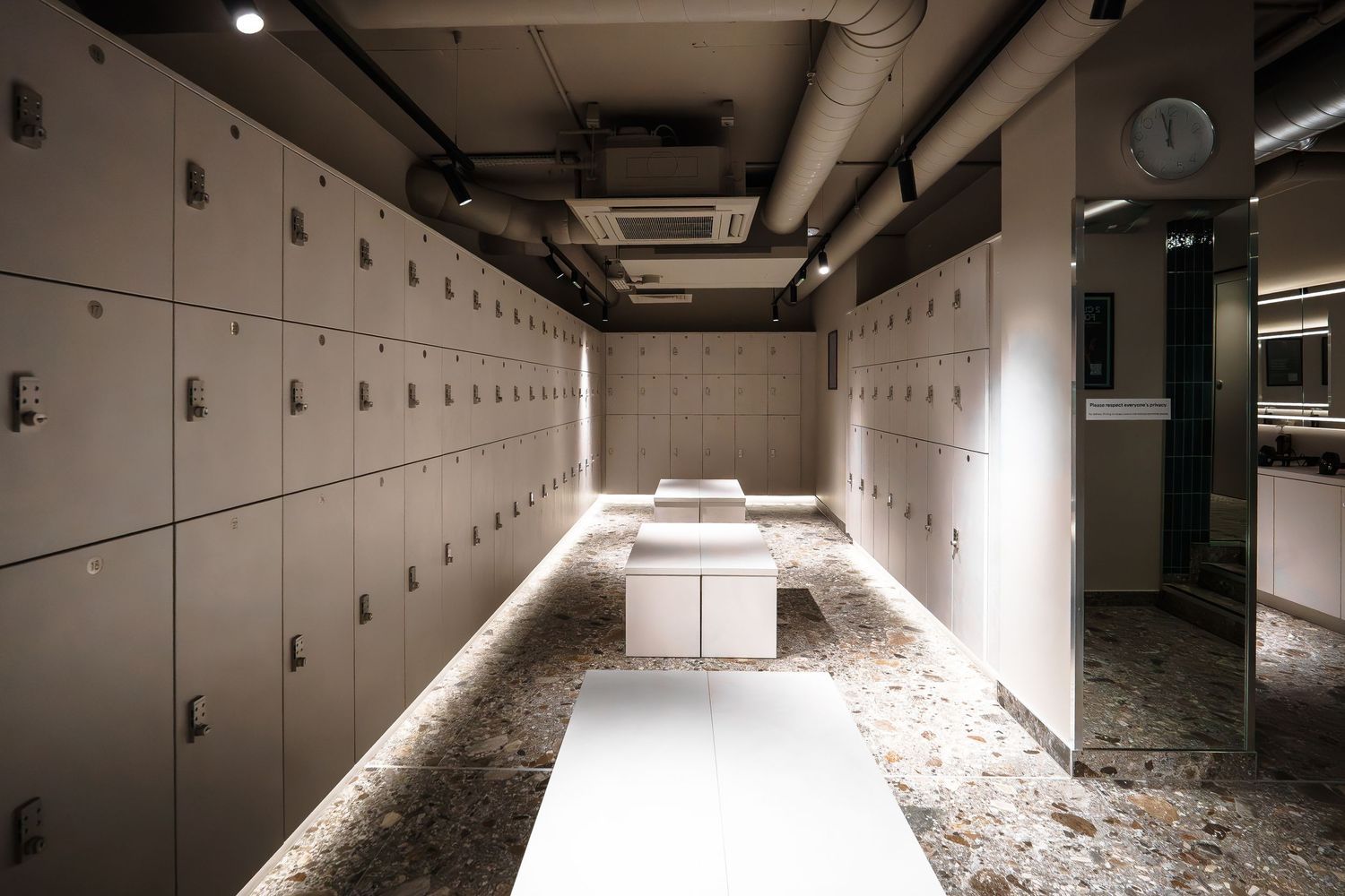 Modern Psycle fitness studio reception area featuring a marble front desk, white sofa, ottomans, and industrial ceiling details.