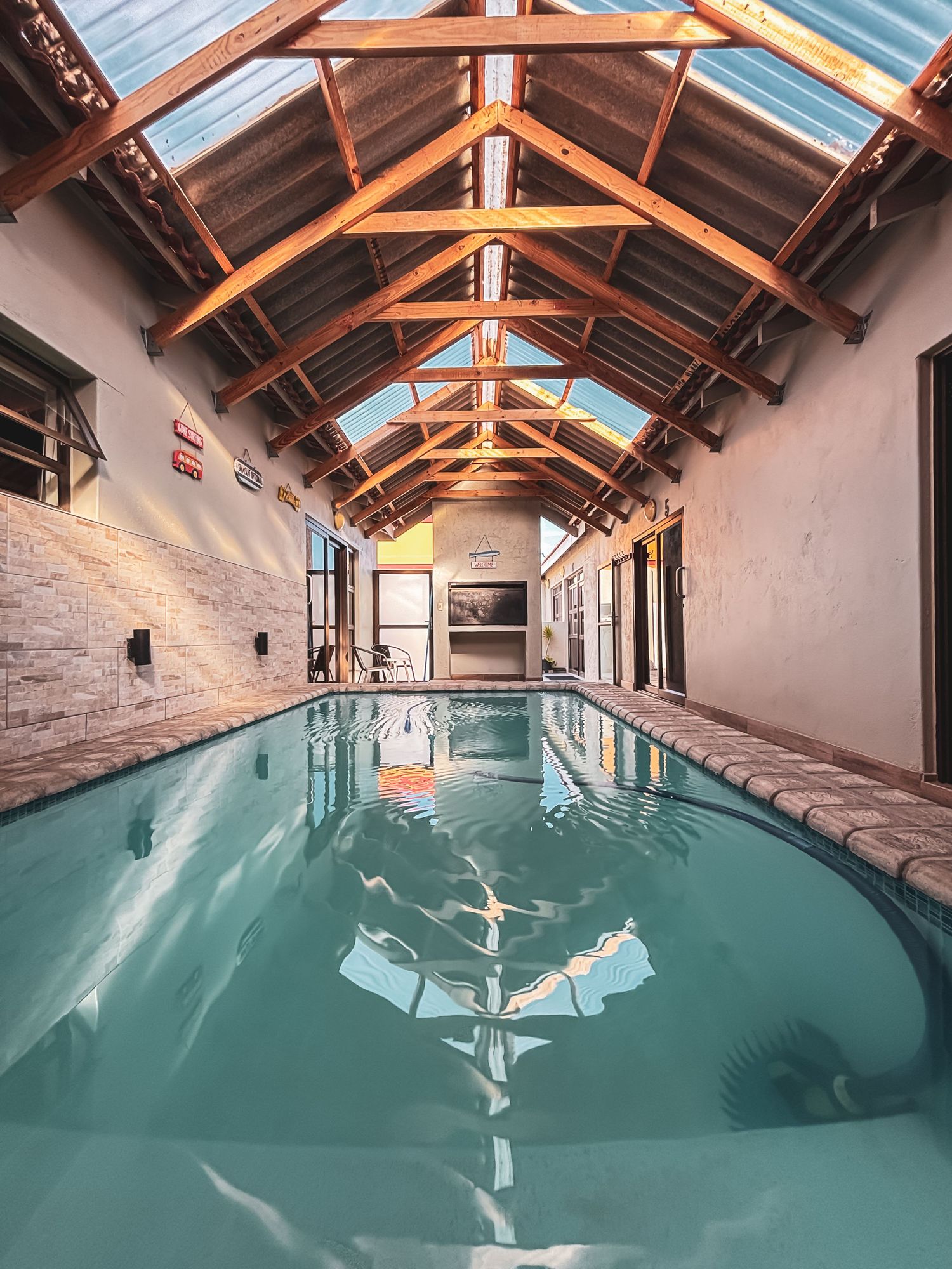 Stunning indoor swimming pool with vaulted wooden beam ceiling and natural skylight — luxury lodge interior photography by Shan Theisinger