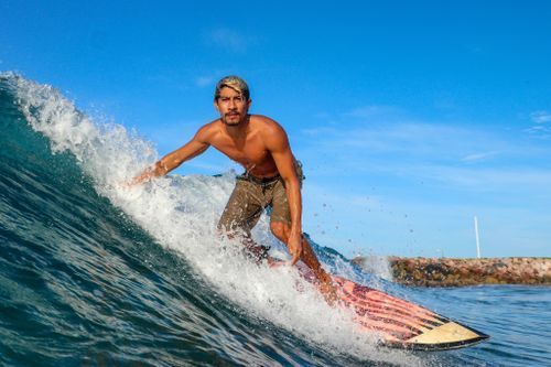 Ixtapa surf photography of a shirtless male surfer riding a wave on a patterned surfboard.
