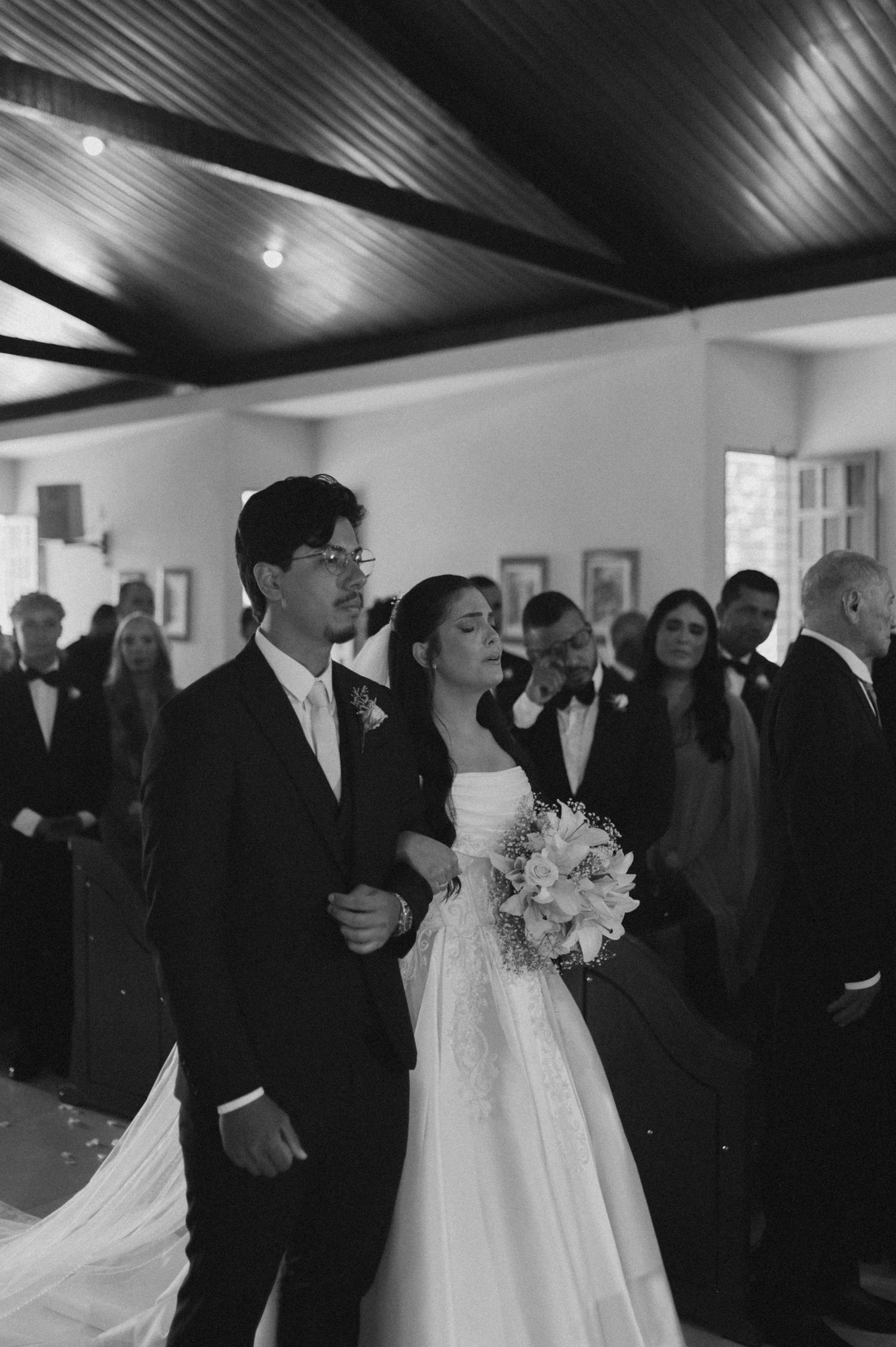 Black and white photo of a bride and groom walking down the aisle together during their wedding ceremony.