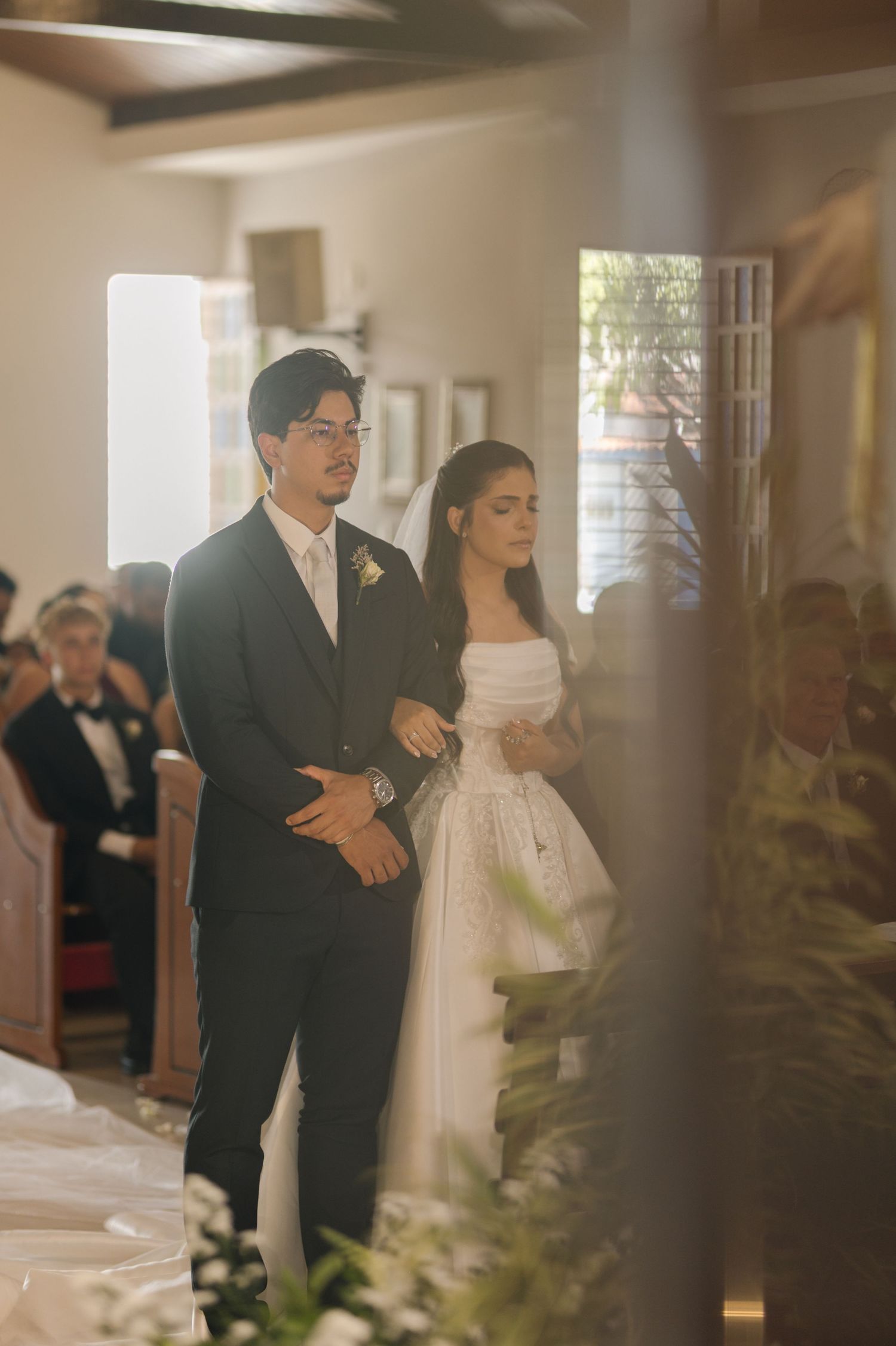 Bride and groom walking down the church aisle during their wedding ceremony in warm golden light.