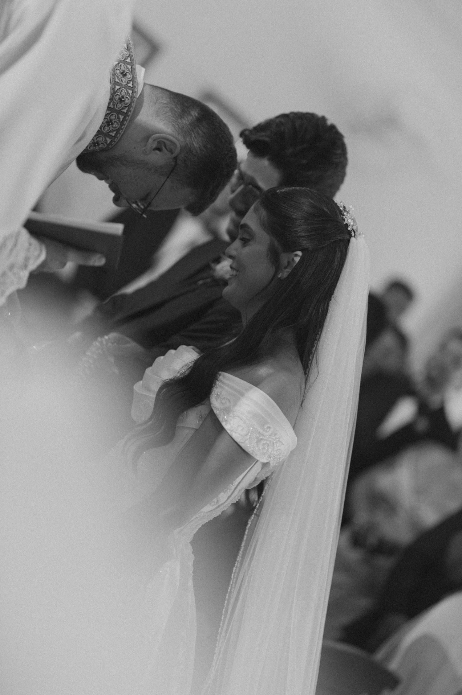 Black and white wedding photo of bride and groom sharing a kiss at the altar during their ceremony.
