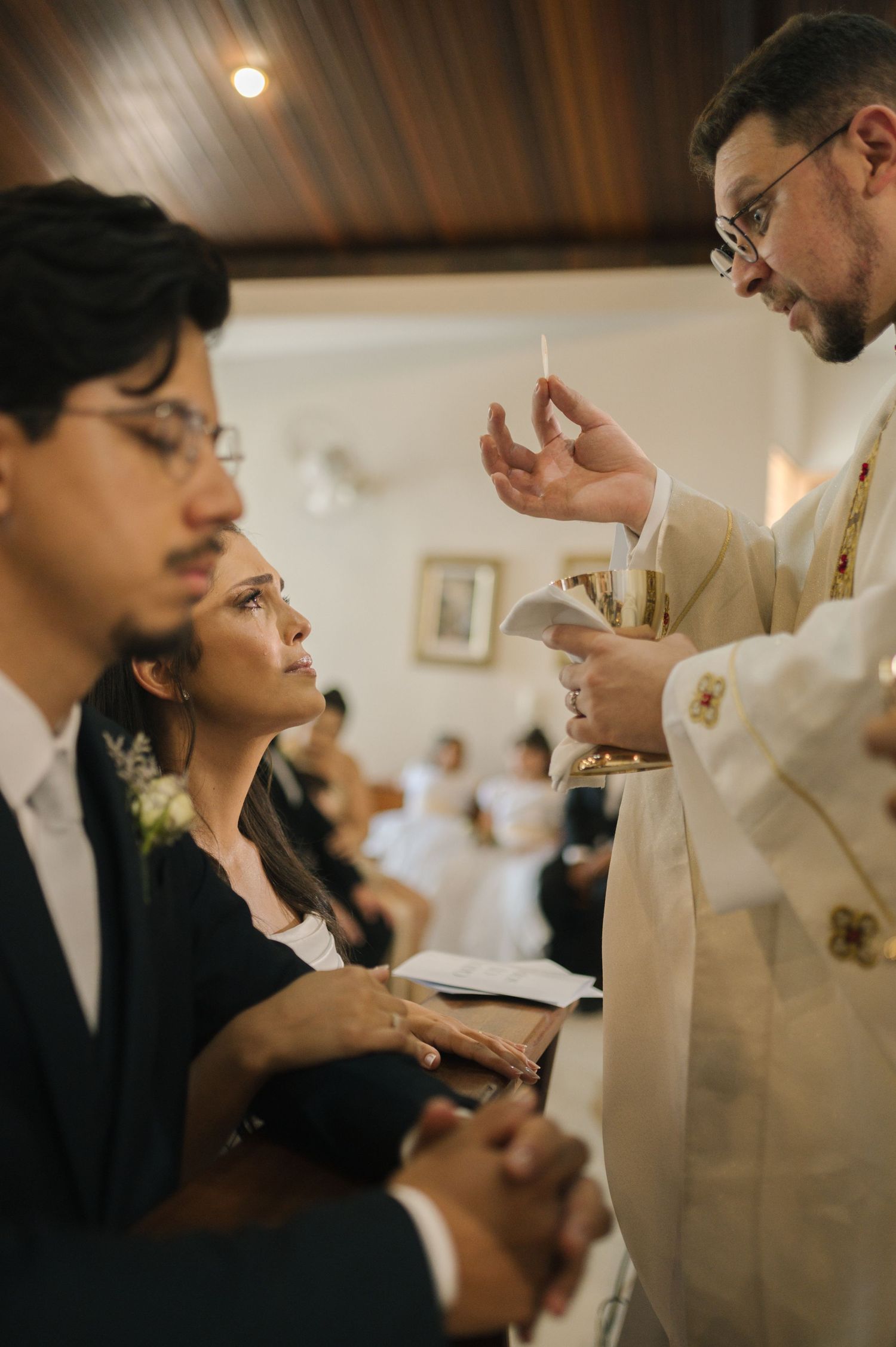 Catholic priest administering Holy Communion to a woman during a church ceremony.