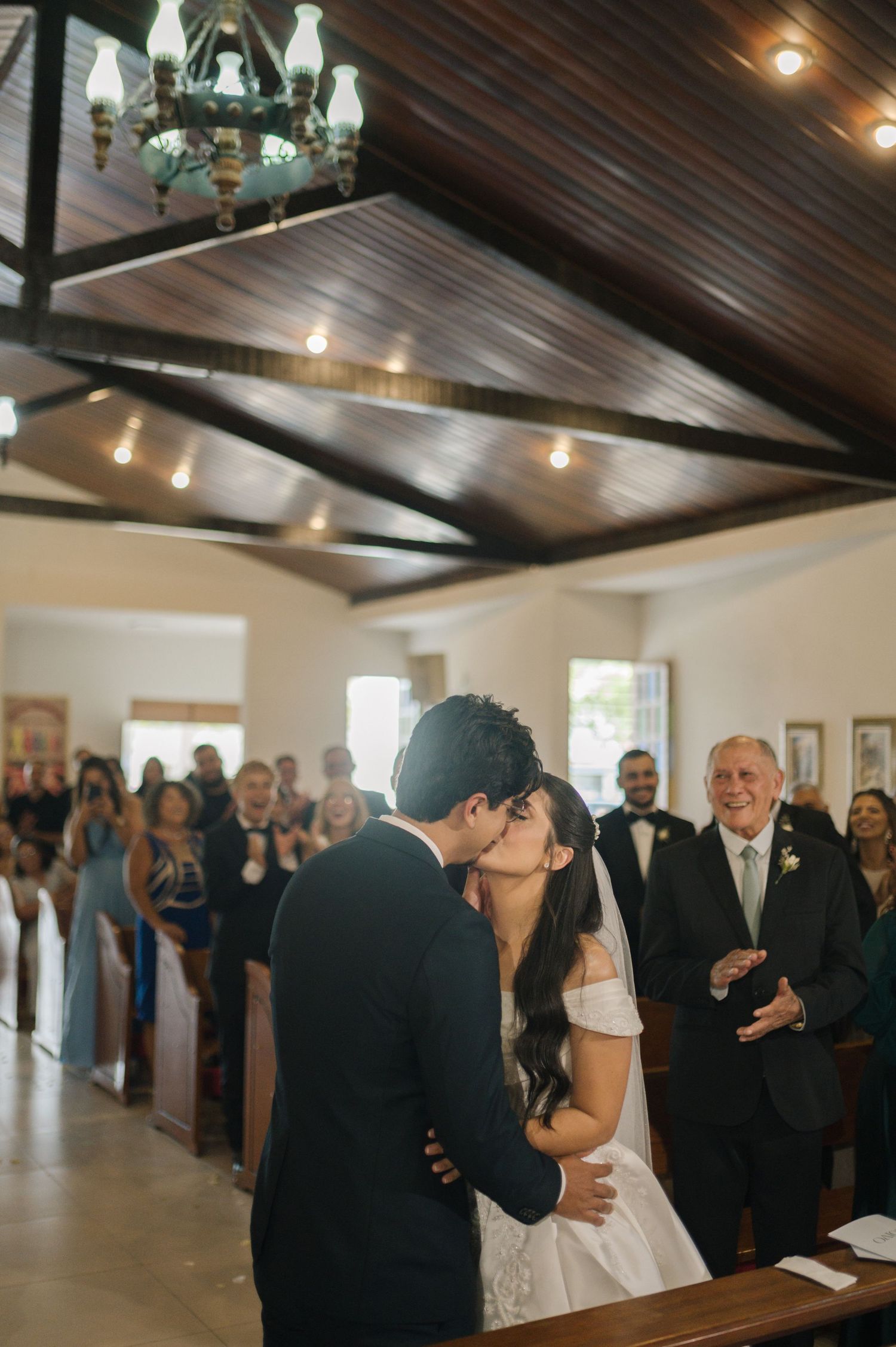 Bride and groom share their first kiss at the altar during a romantic wedding ceremony in a charming chapel.