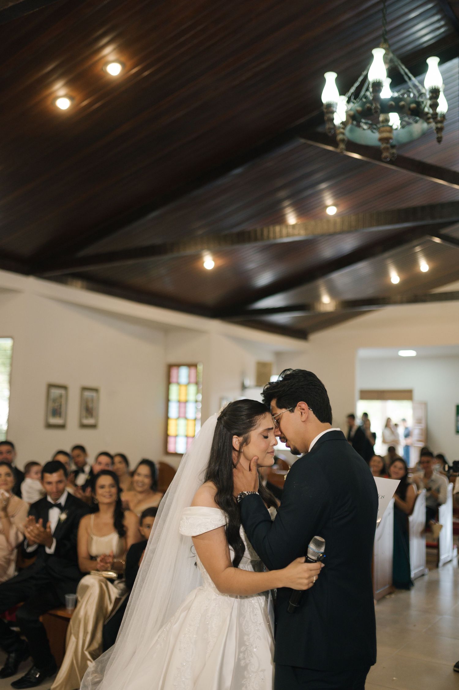 Bride and groom share an intimate moment during their wedding ceremony in a elegant church filled with guests.
