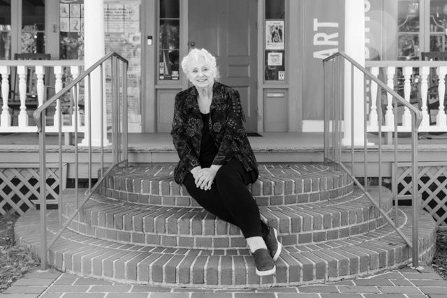 Woman sitting on brick steps outside an art gallery in black and white photo.