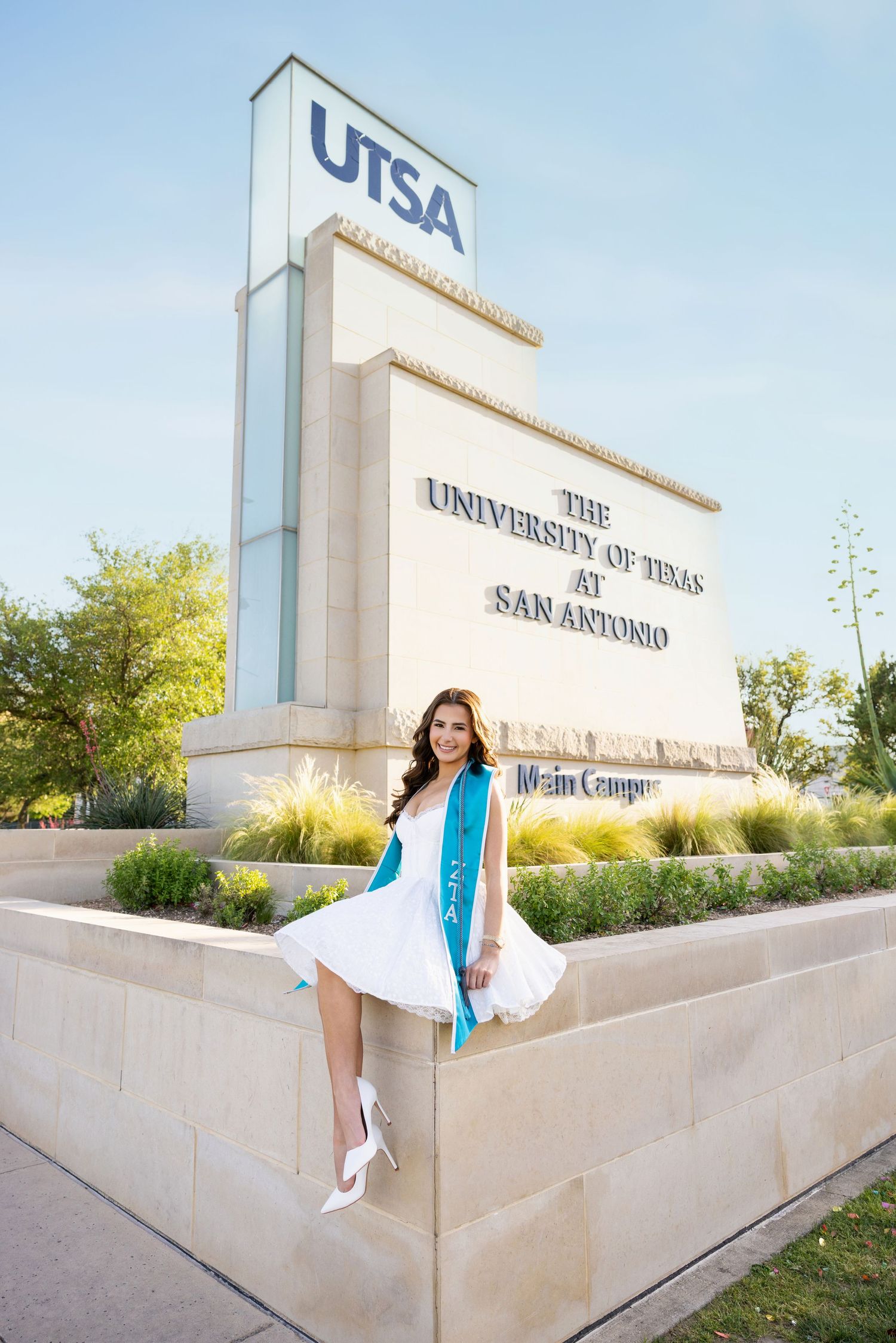 Smiling female graduate in black cap and gown wearing a First Generation stole at Texas Tech University.