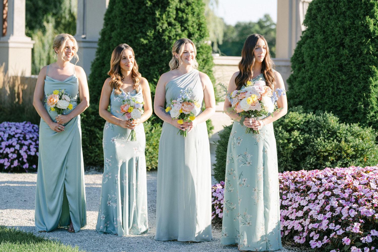 Armour House Wedding - Four bridesmaids in sage green gowns holding colorful bouquets stand outdoors.
