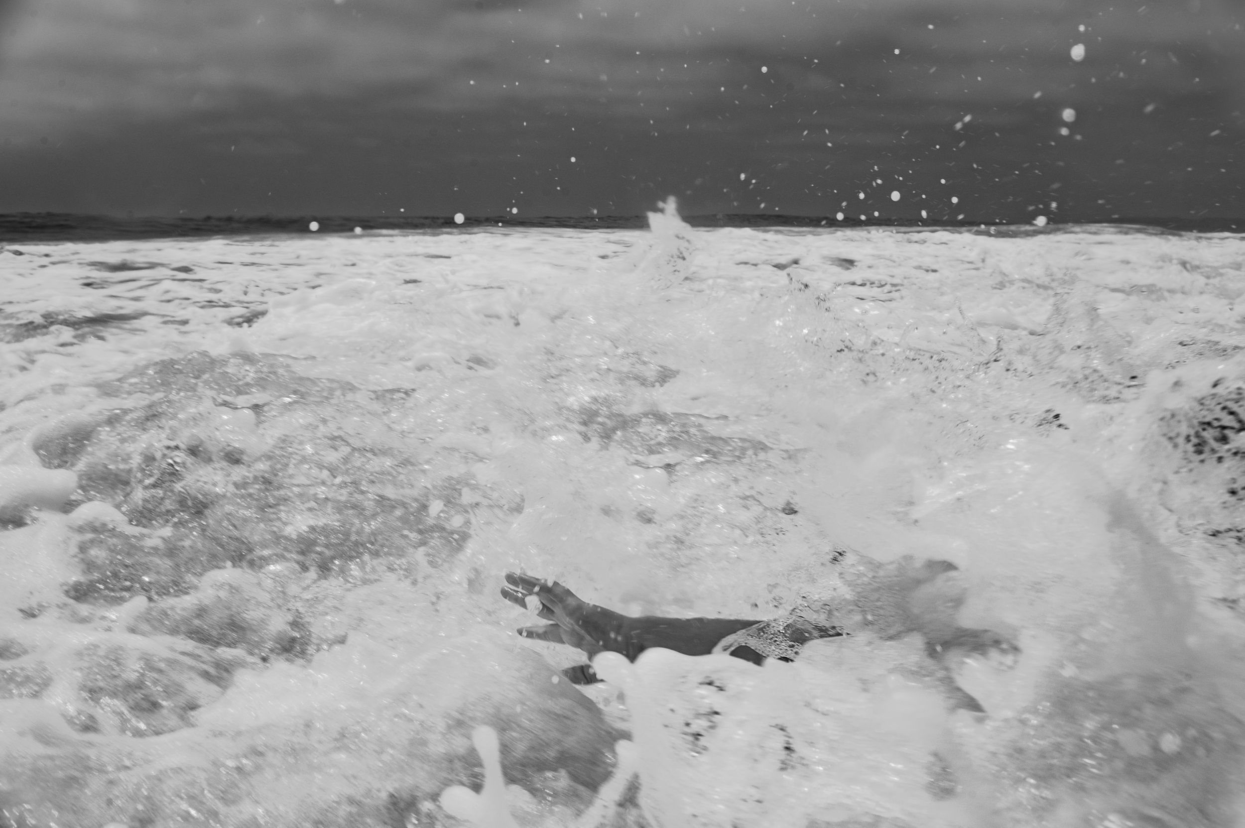 Black and white photo of powerful ocean waves crashing with white sea foam and spray.