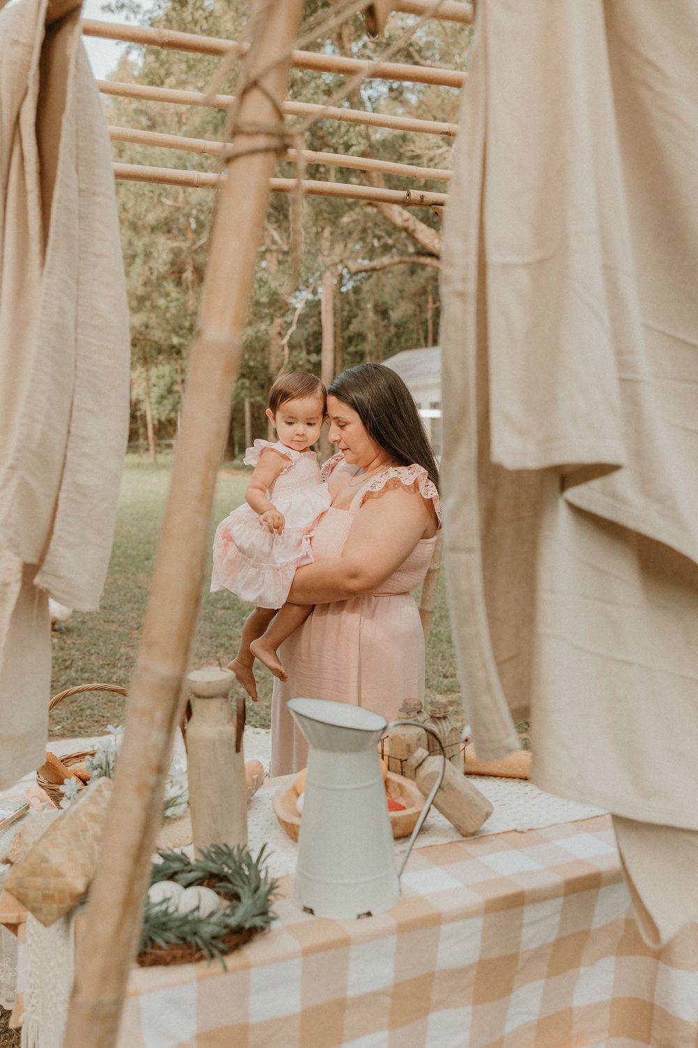 A vintage-inspired picnic scene with hanging linens and a metal pitcher on a gingham tablecloth in warm earth tones.