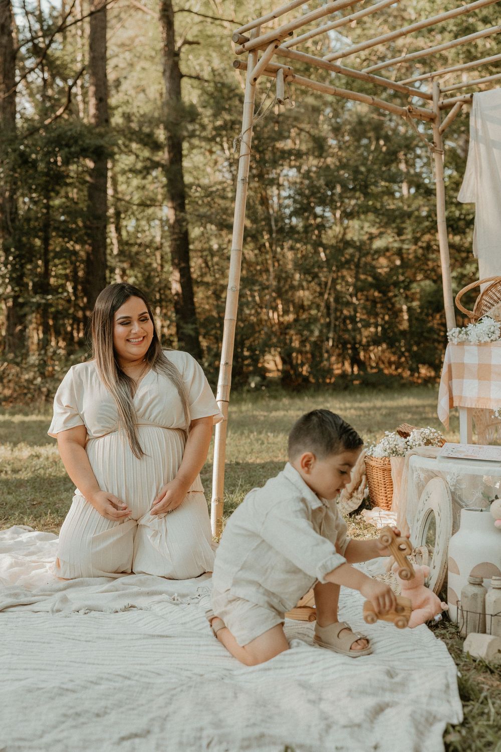 A picturesque outdoor picnic setting features a cozy blanket and rustic decor in a sunlit wooded area.
