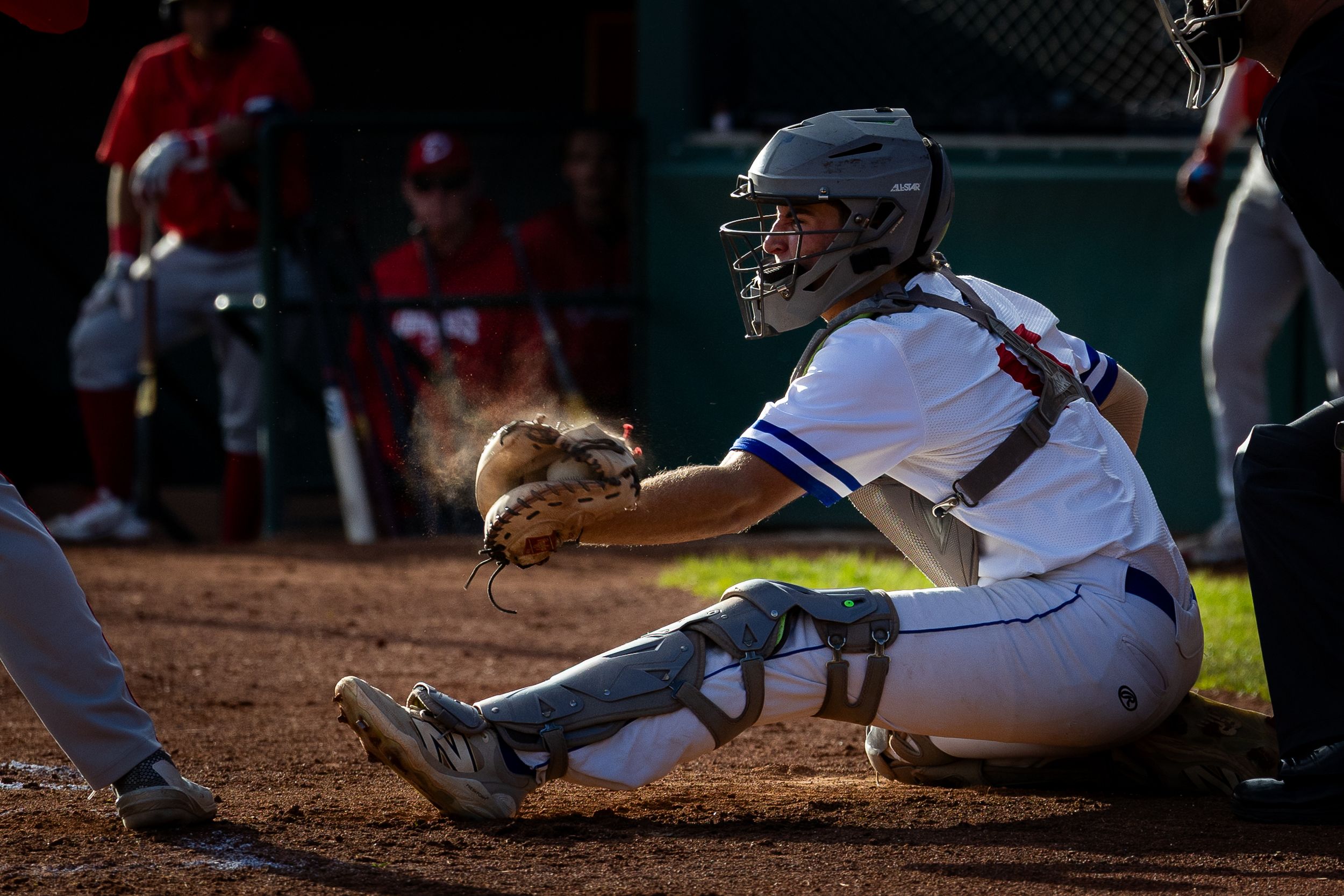 Brooks Bombers (WCBL) catcher slides to home plate in cloud of dust during intense game action.