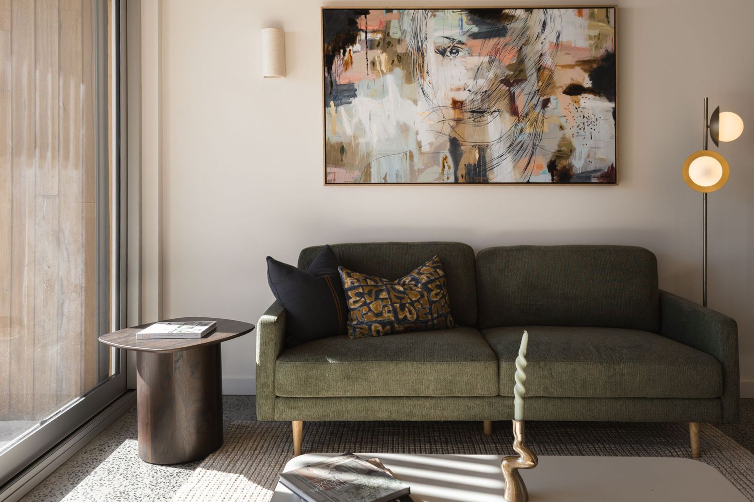 Cozy living room with green velvet sofa, leopard print pillow, abstract wall art, and warm natural light from large window.
Middleton Fields
