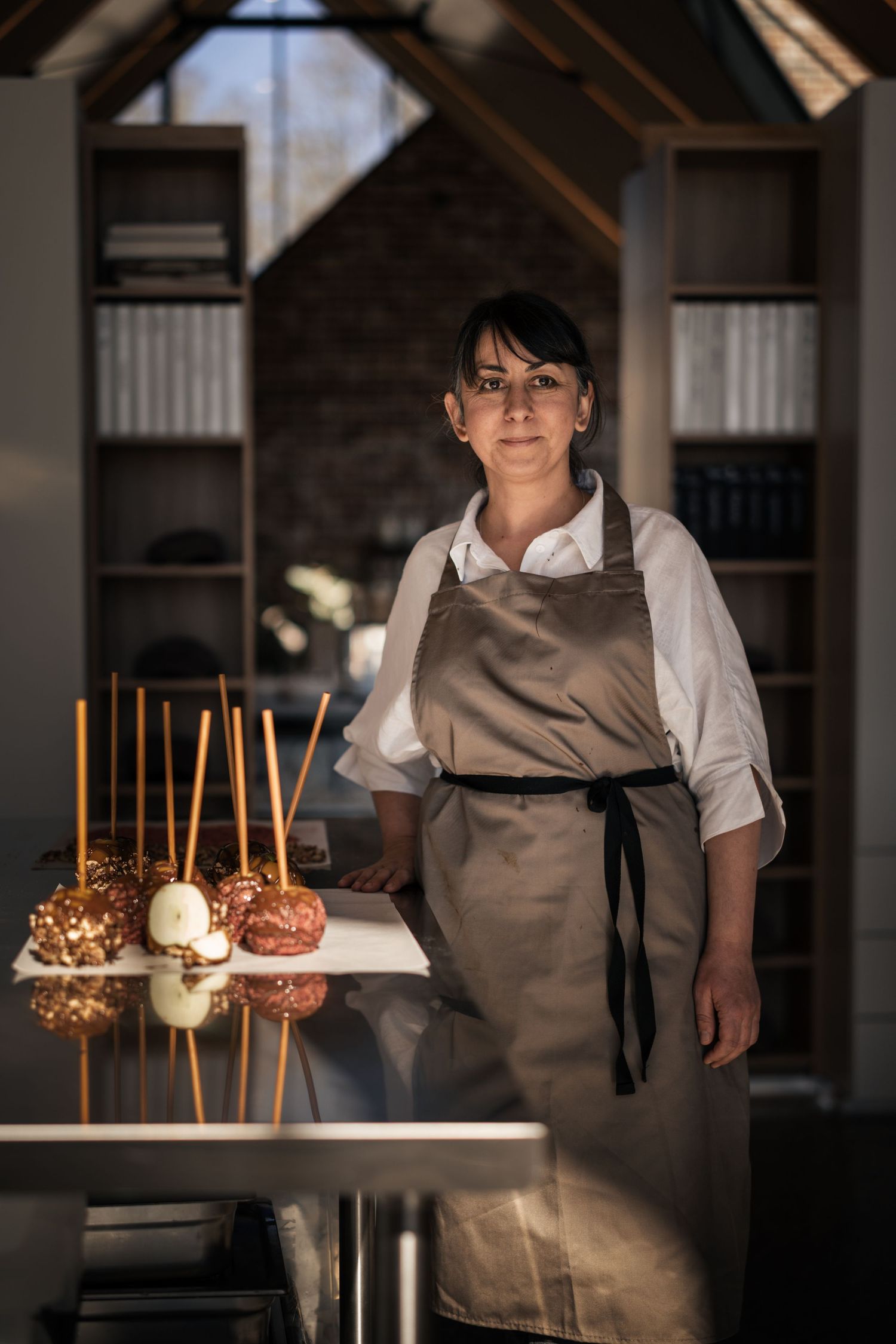A female chef in a beige apron stands beside candied apples on sticks in a modern kitchen.

Sisko Chocolates