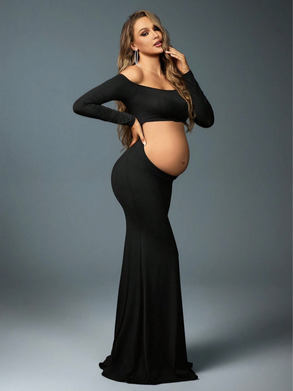 Black maternity mermaid gown with long sleeves and cutout midriff design.
