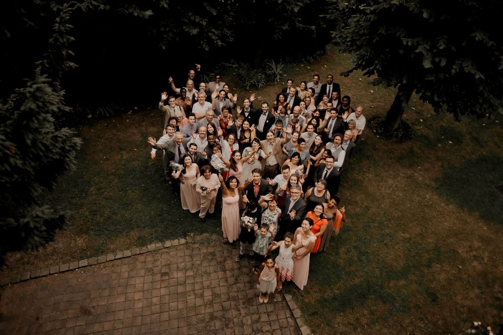 Aerial view of wedding guests arranged in a heart shape formation outdoors.