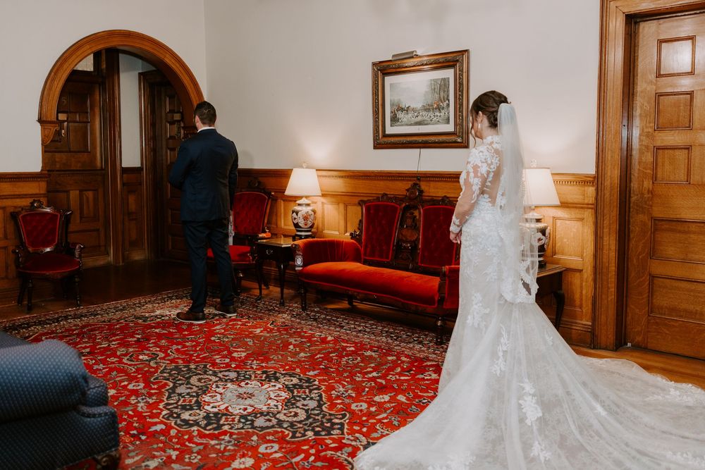 Bride and groom sharing a first look moment in an elegant wood-paneled room.
