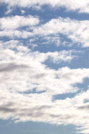 Blue sky with scattered white fluffy cumulus clouds on a bright sunny day.
