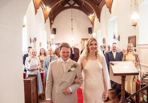 Bride and groom walking down the red carpet aisle of a traditional church after ceremony.