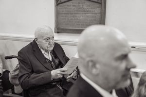 Elderly man in wheelchair reading a paper during a church wedding ceremony.