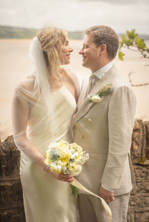 Bride and groom gazing at each other with wedding bouquet by a waterside scenic backdrop.