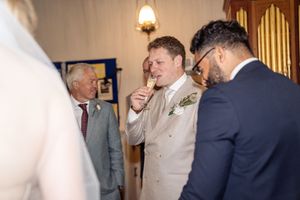 Groom laughing with guests in a church during wedding reception celebrations.
