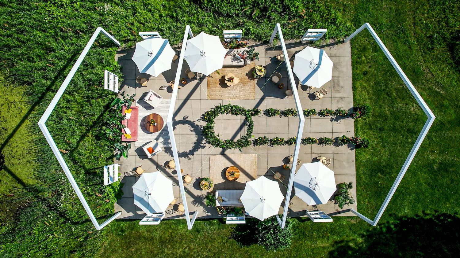 Top-down aerial view of an outdoor patio with white umbrellas and geometric white frame structures.