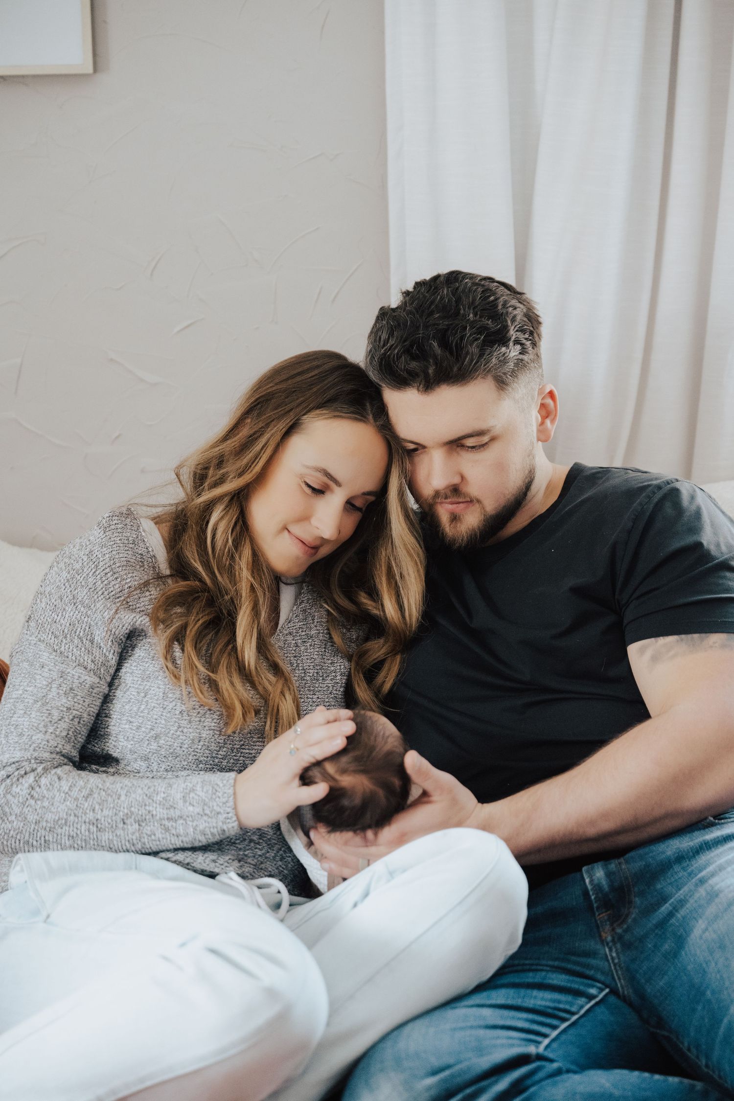 portrait of parents snuggling and admiring newborn baby during in home lifestyle newborn session in north hudson, wi