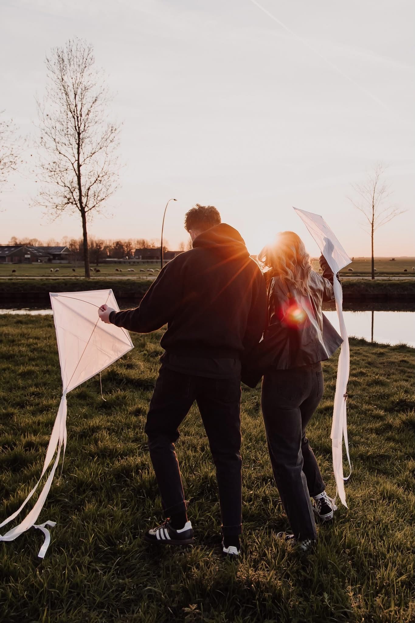 Couple enjoying a sunset kite flying session in an outdoor natural setting.