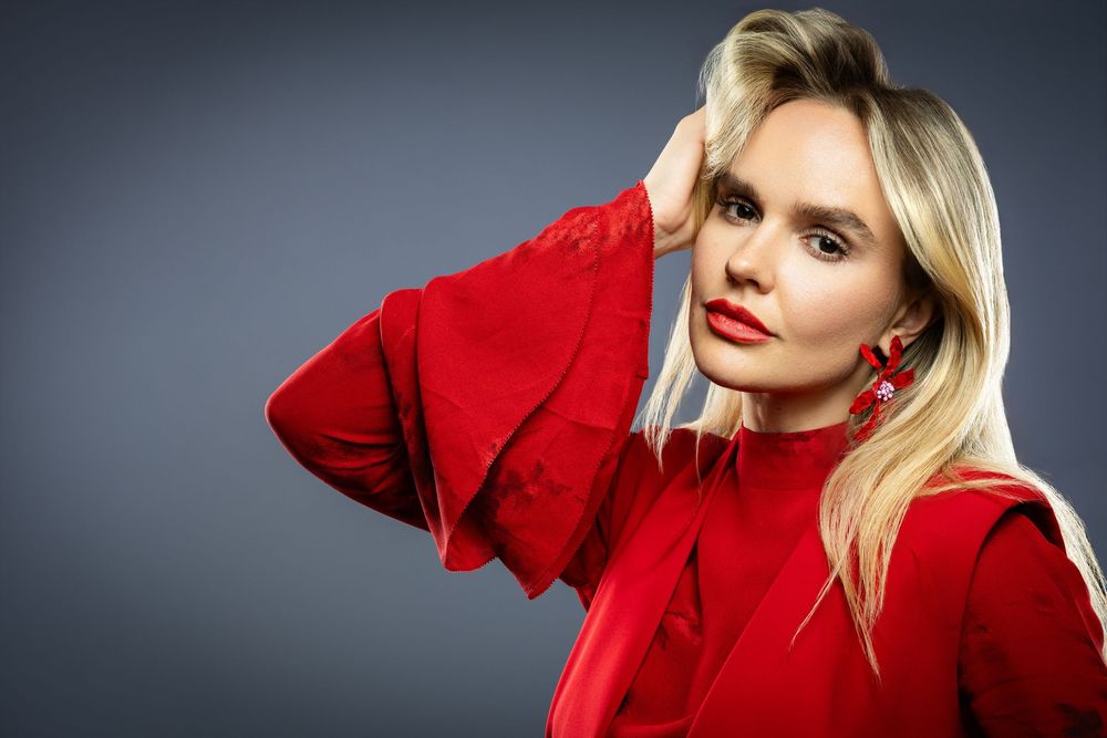Fashion portrait of person in bright red sweater against gray background.