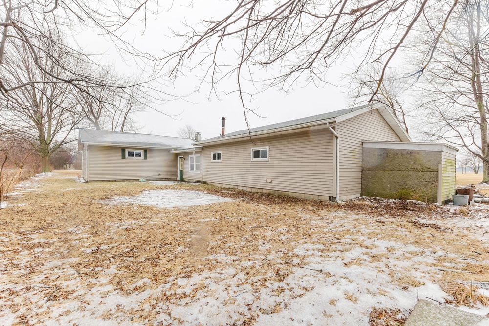Ranch-style home exterior with tan siding, attached garage, and snow-covered yard in winter.